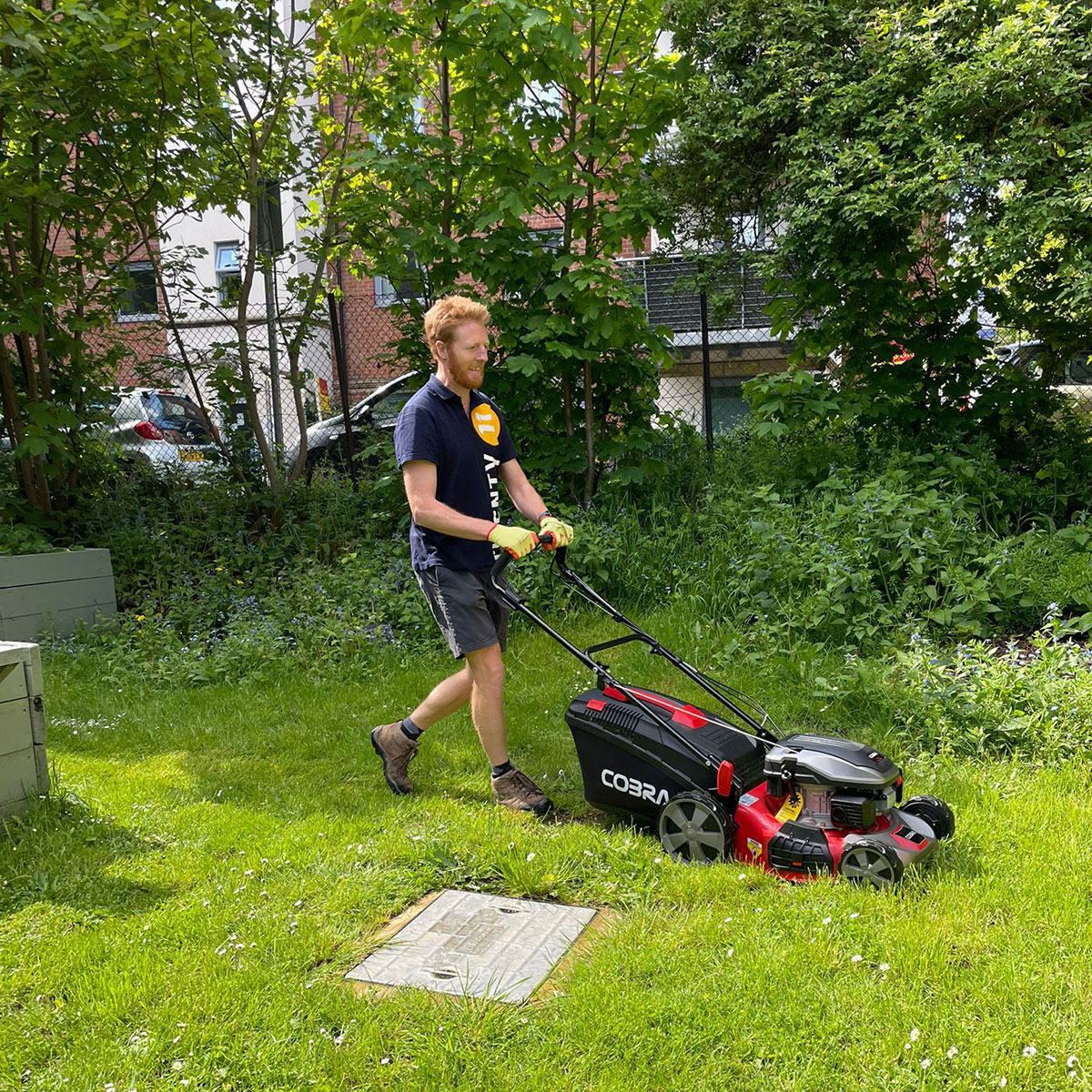 A member of the Twenty11 team mowing the grass at Wycombe Arts Centre